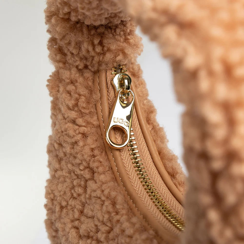 UGG Momo 淺棕色羊羔毛包 拉鍊特寫，金色五金拉鍊頭上刻有 UGG 標誌。