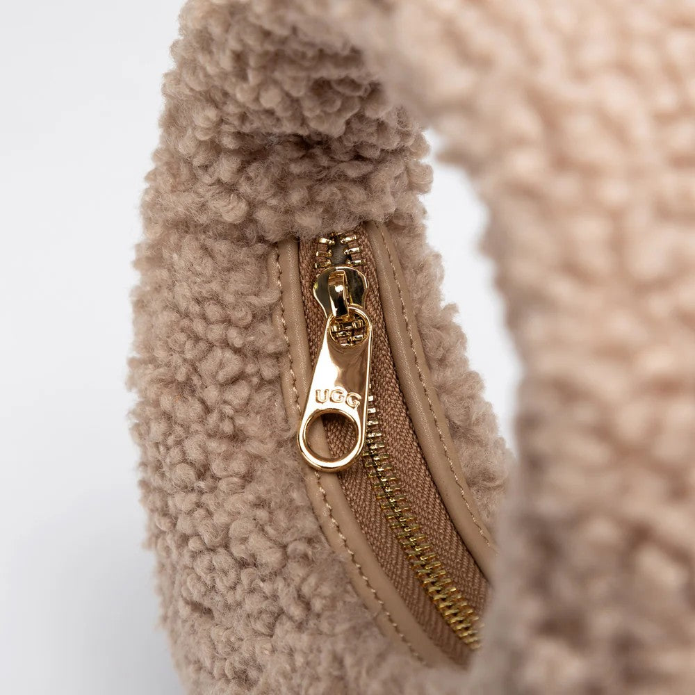 UGG Momo 奶茶棕羊羔毛包 拉鍊特寫，金色五金拉鍊頭上刻有 UGG 標誌。